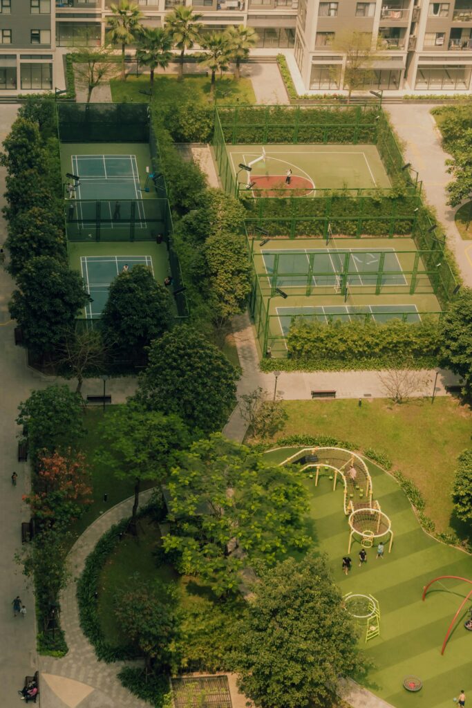Aerial shot of an urban park featuring tennis courts and green spaces in a city environment.